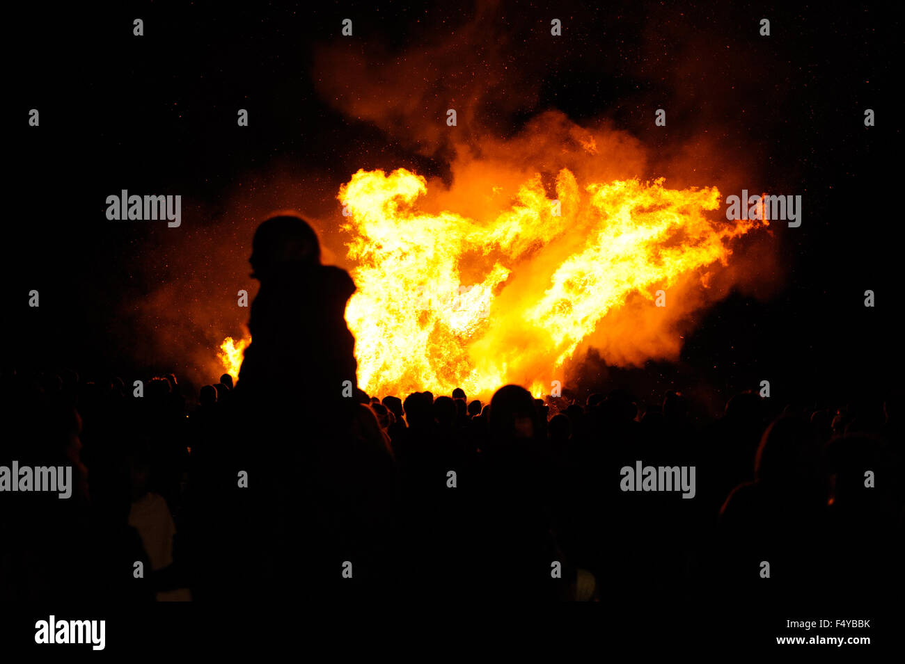 People are silhouetted against the flames of a large bonfire lit to celebrate  November the 5th, also known as Bonfire Night, in the village of Firle in East Sussex, England. Stock Photo