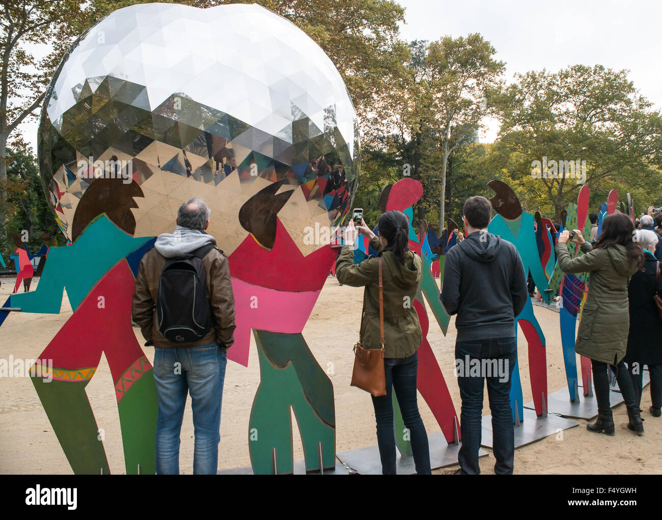 New York, United States. 24th Oct, 2015. Spectators of the event snap photos between the 70 metal figures of Gabarron's installation.To commemorate the 70th anniversary of the United Nations Charter, United Nations and New York City officials joined to inaugurate the opening of Cristobal Gabarron's sculptural installation titled 'Enlightened Universe:' a reflective metal sphere surrounded by an overlapping ring of brightly-colored life-size figures holding hands. © Albin Lohr-Jones/Pacific Press/Alamy Live News Stock Photo