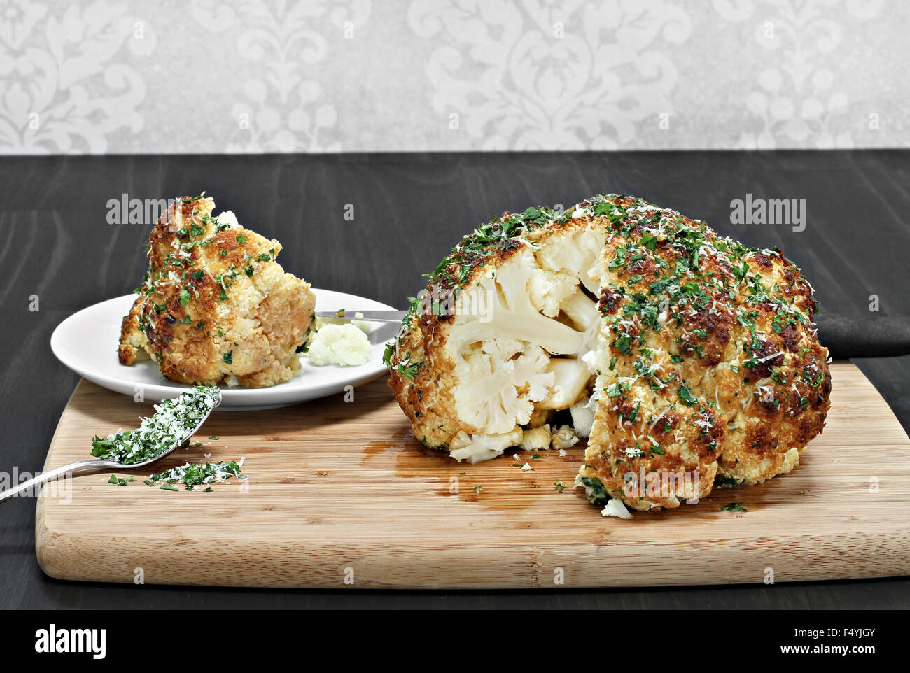 One whole roasted cauliflower head with a slice removed revealing inside appearance. Stock Photo