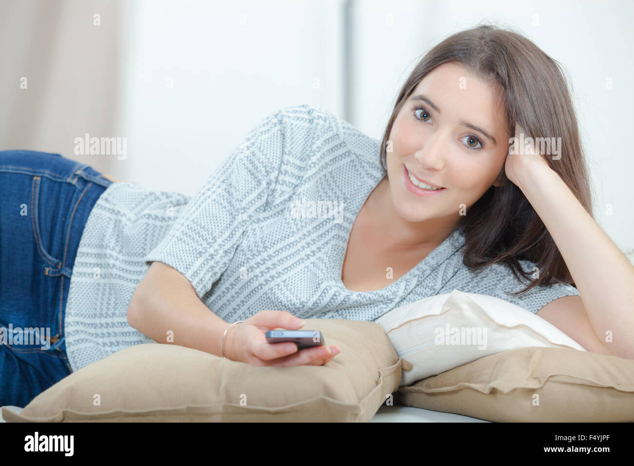 Sending a text message from her sofa stock photo alamy