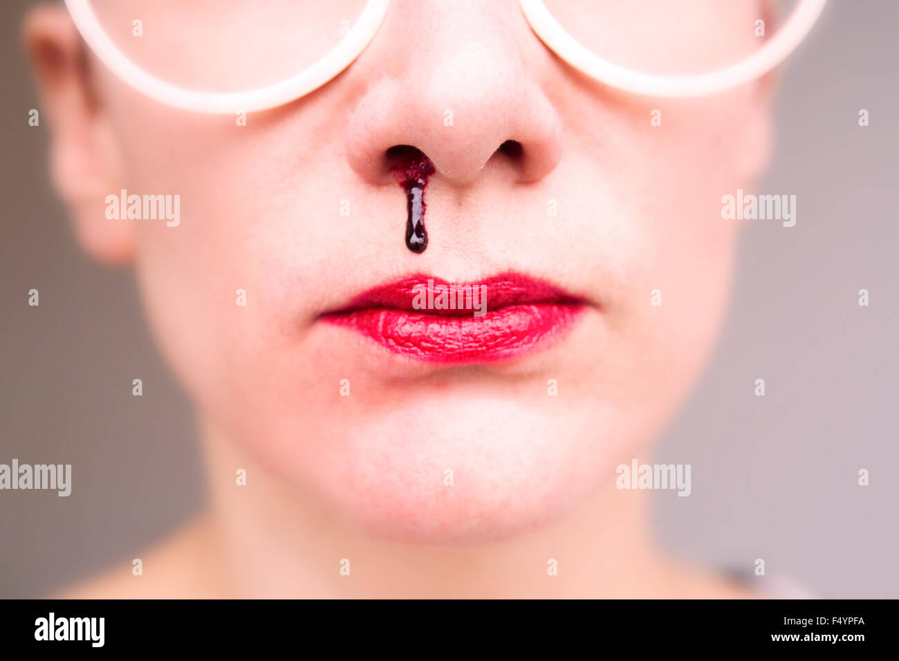 closeup of woman wearing glasses and having nosebleed Stock Photo