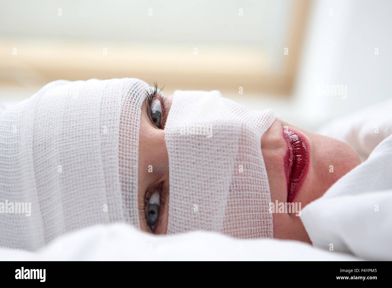 closeup of beautiful woman in bed with bandages wrapped around her head Stock Photo