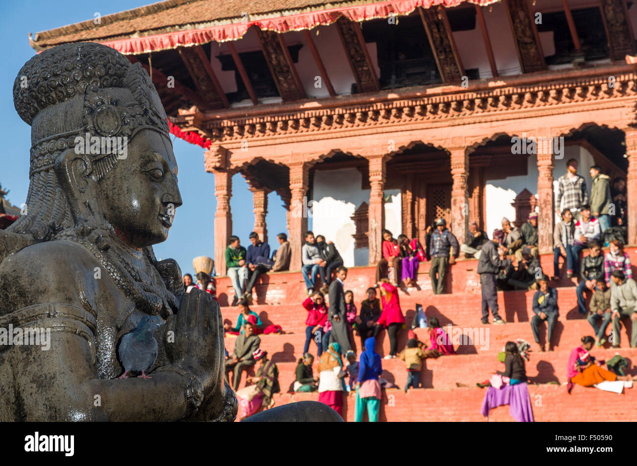 Local people resting on temple steps at Durbar Square, statue of Garuda in foreground Stock Photo
