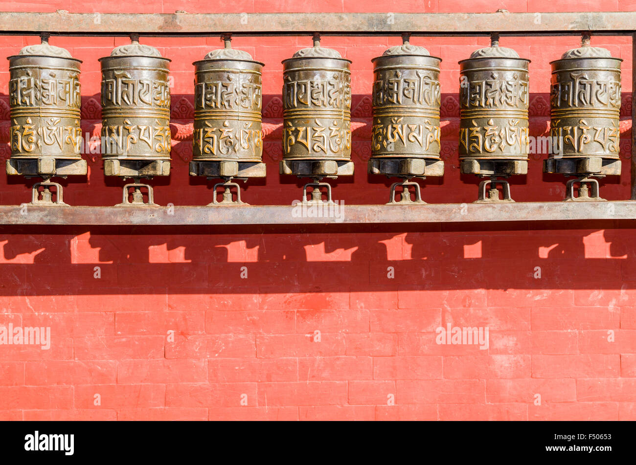 Buddhist prayer wheels in front of a red wall at Swayambhunath Stupa ...