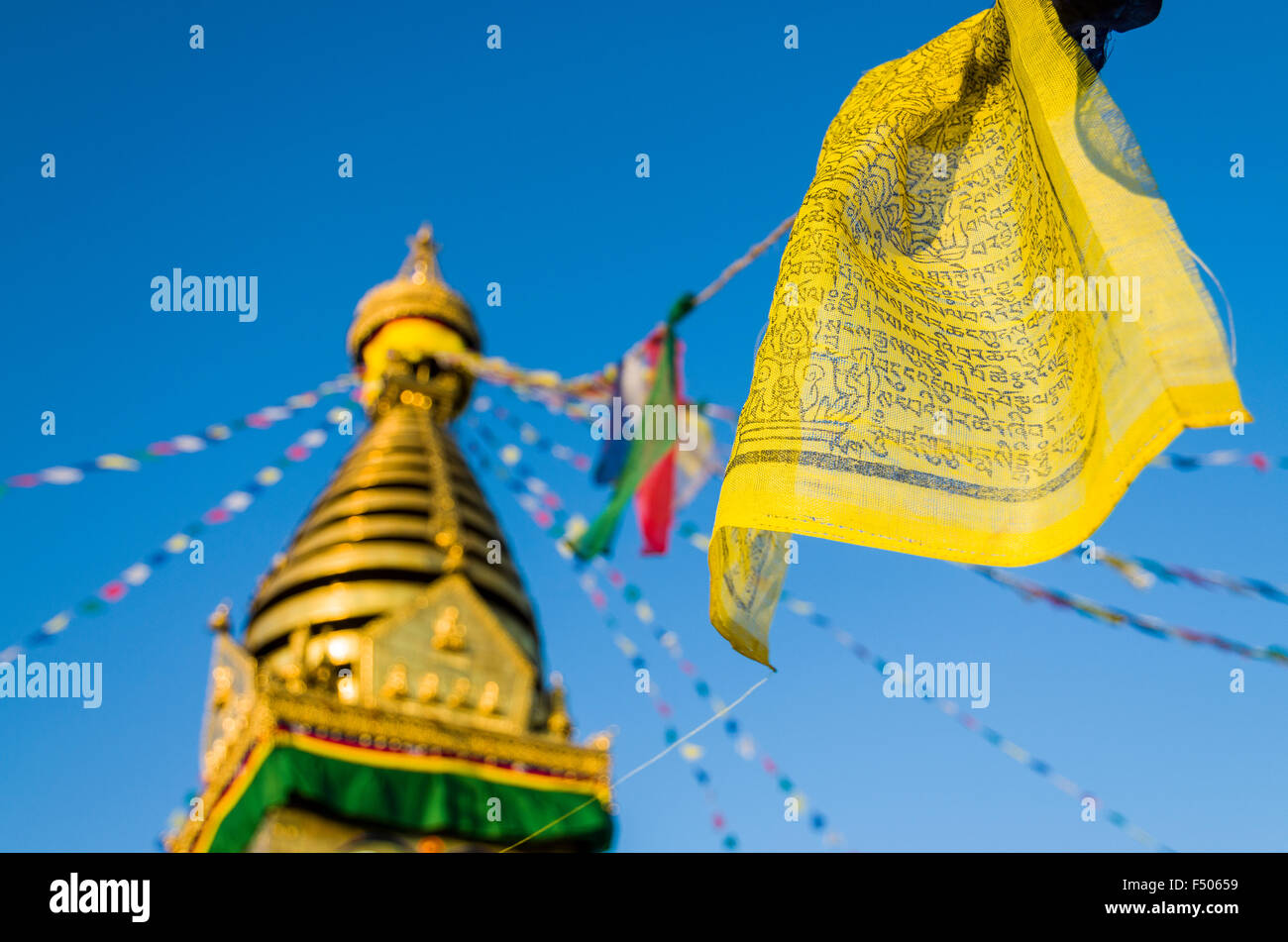 Yellow buddhist prayer flag with Swayambhunath Stupa, the Monkey Temple, in the background Stock Photo