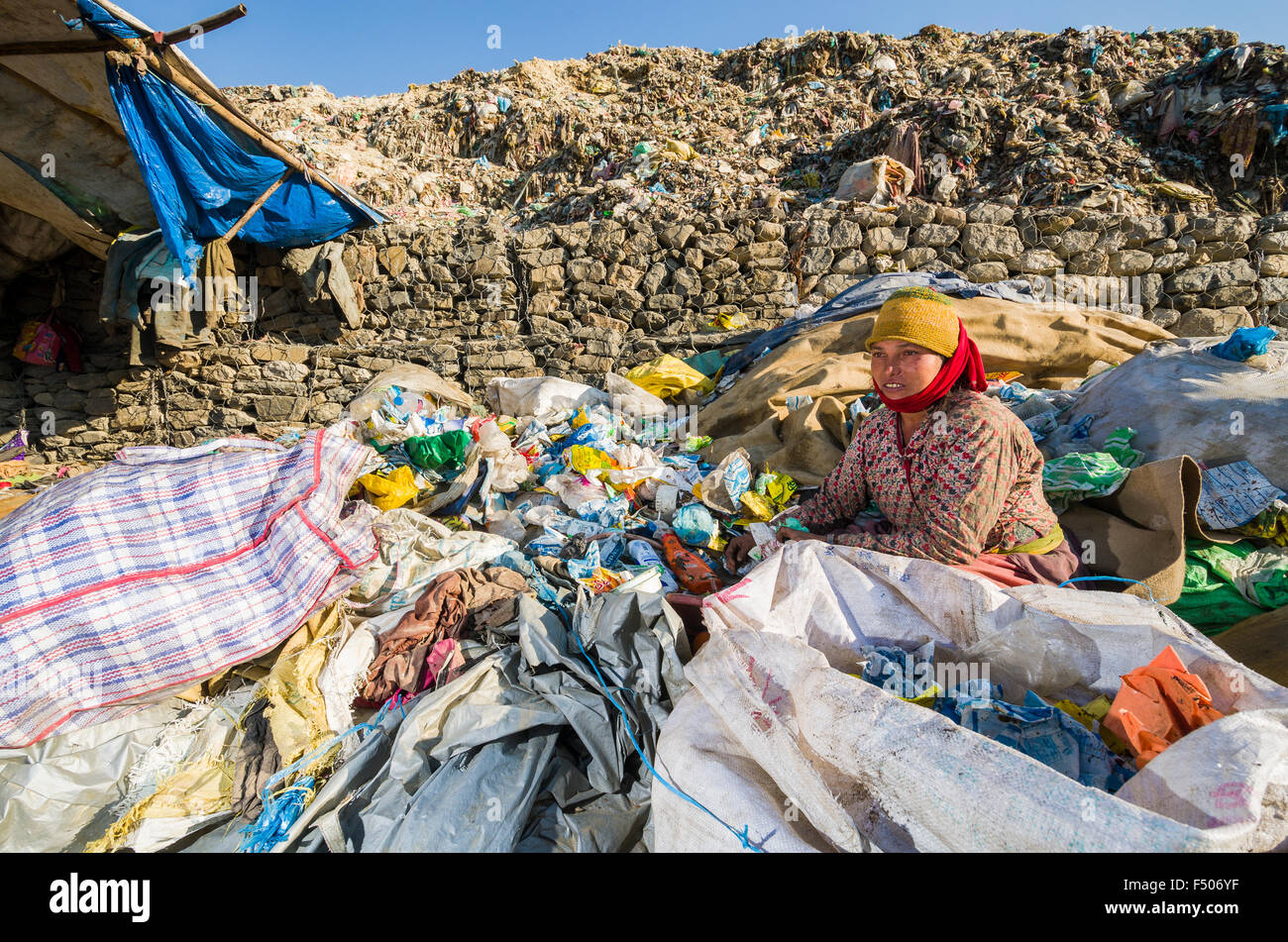 Woman sitting in between and sorting out garbage at Aletar garbage dump, earning 300-400 nepali rupees a day Stock Photo