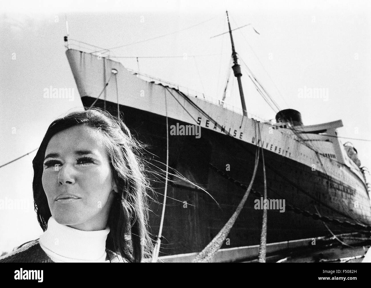 A prospective female student poses in front of Seawise University, the former RMS Queen Elizabeth, while it was docked in 1971 at Port Everglades, Florida, USA. Once the world's largest passenger ship, it was intended to become a floating school that sailed the globe. However, a year later the ocean liner caught fire and sank in Hong Kong's Victoria Harbor while it was being refurbished as a floating campus for students. Parts of the 83,000-ton vessel that were not salvaged became a navigational hazard in the harbor until being buried with landfill in the late 1990s. Historical photo. Stock Photo