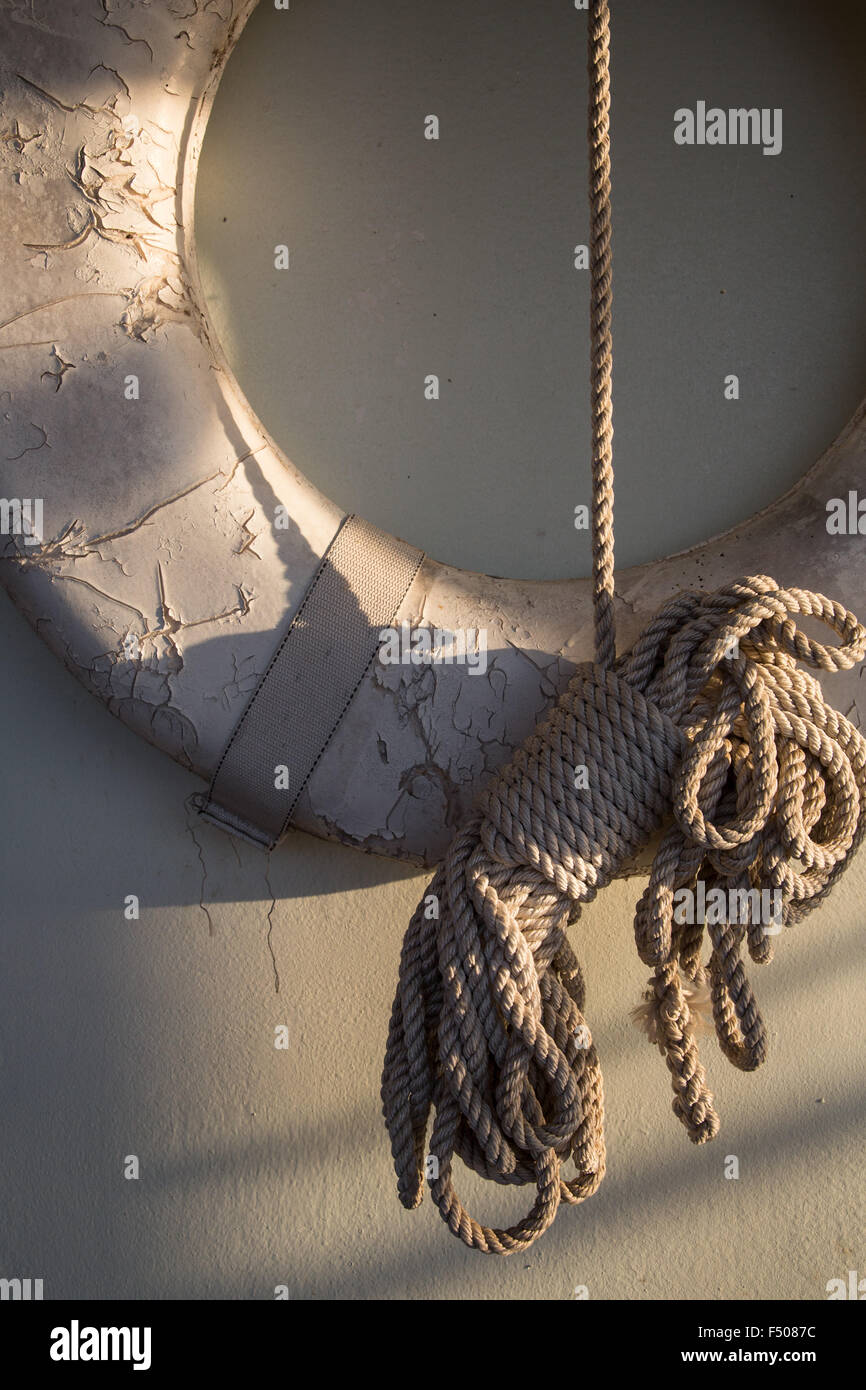 An old, faded lifesaver ring and nautical rope Stock Photo