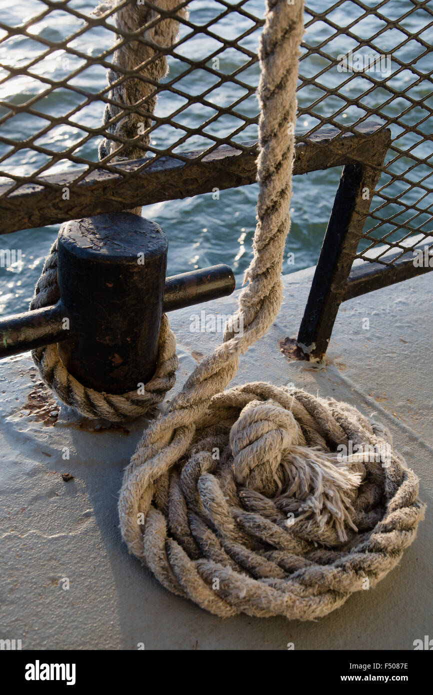 Thick nautical rope attached to a metal tie down post Stock Photo