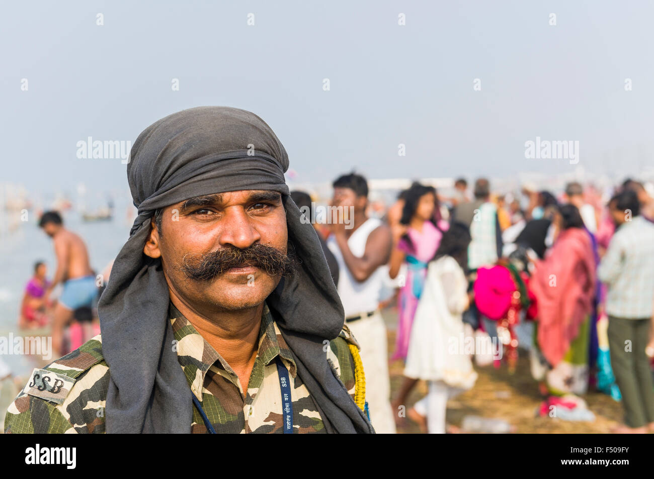 Portrait of a policeman within people taking bath at the Sangam, the confluence of the rivers Ganges, Yamuna and Saraswati, at K Stock Photo