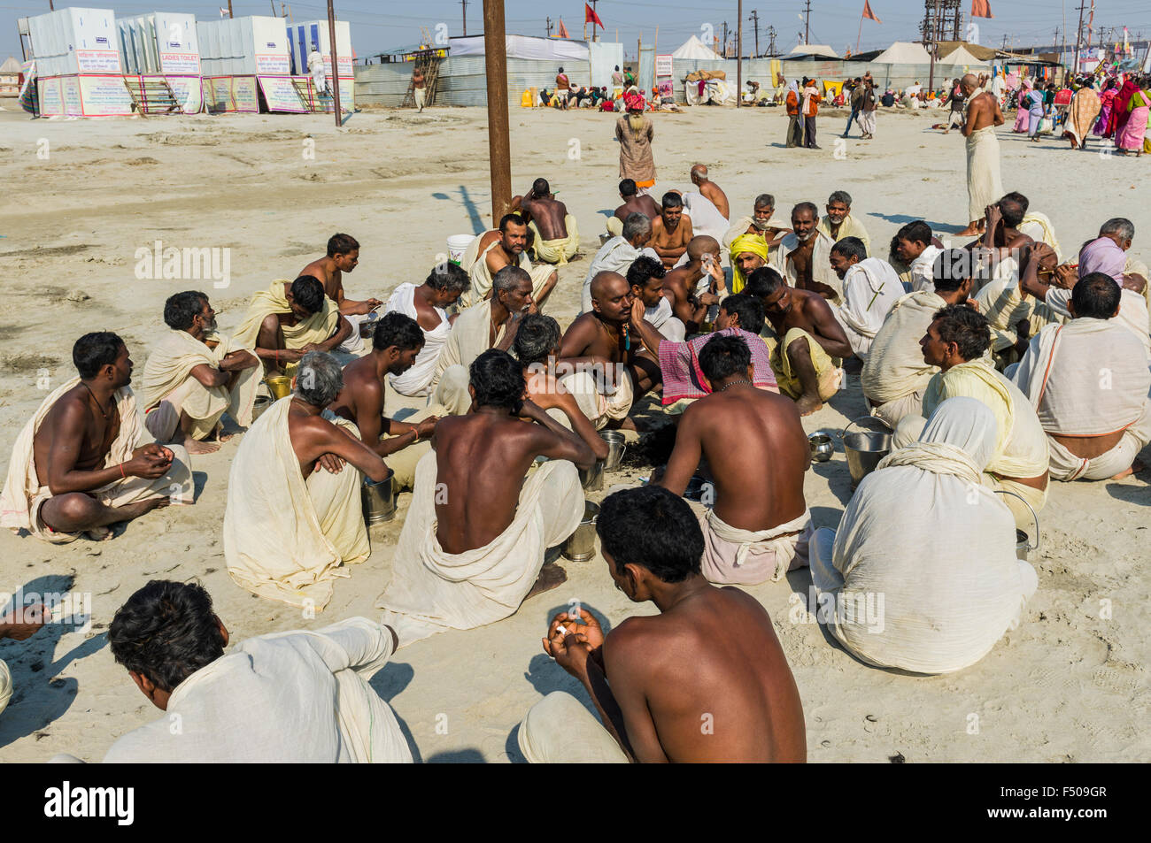 Group of male pilgrims getting their heads shaved at the Sangam, the confluence of the rivers Ganges, Yamuna and Saraswati, at K Stock Photo