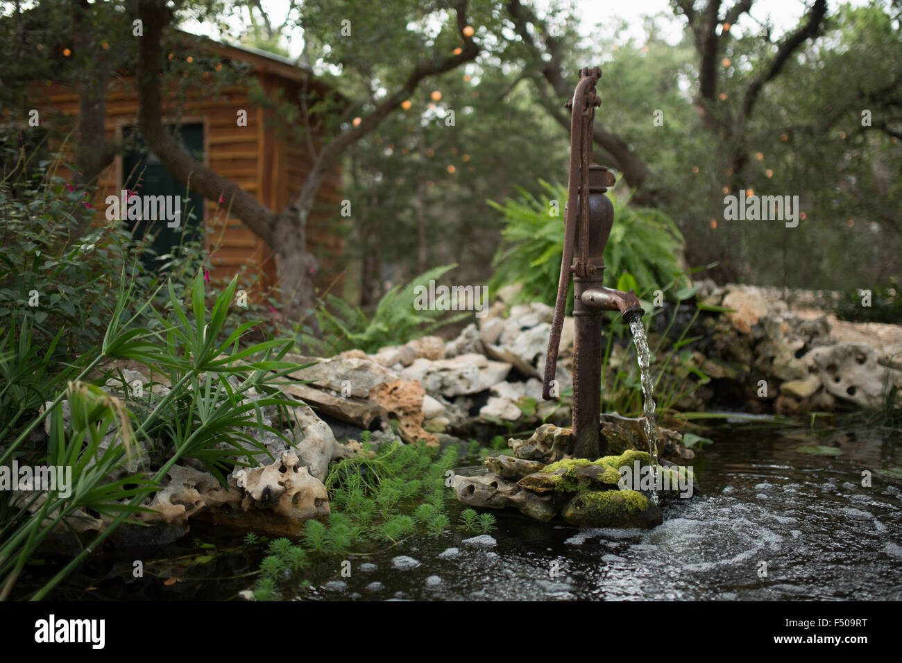 Water Flows Out Of An Old Fashioned Pump Into An Ornamental Pond