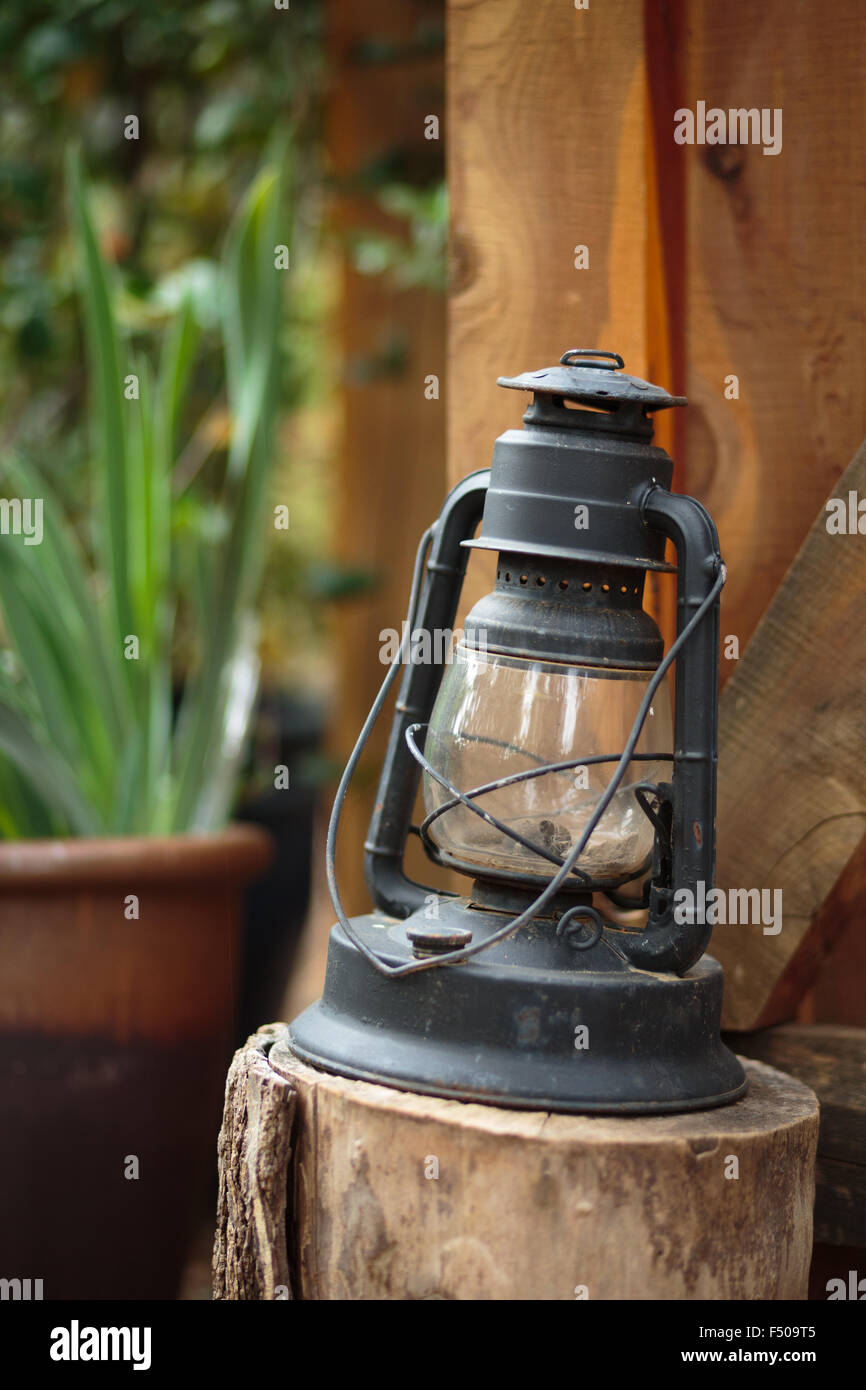 An old-fashioned gas lantern on a stump in front of a wooden cabin Stock Photo