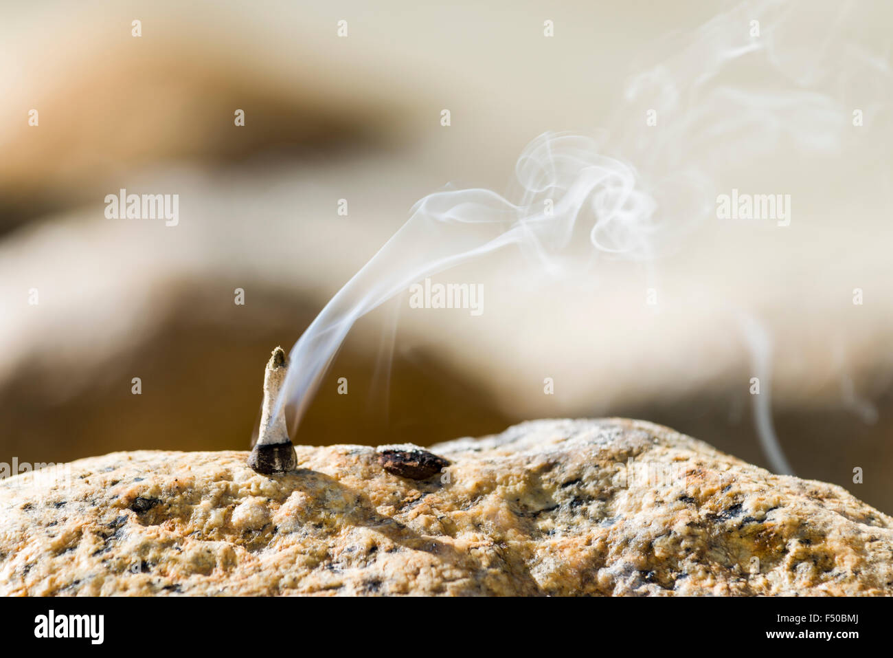 Incence, used for religious ceremonies, is smoking on a rock at the banks of the river Ganges Stock Photo