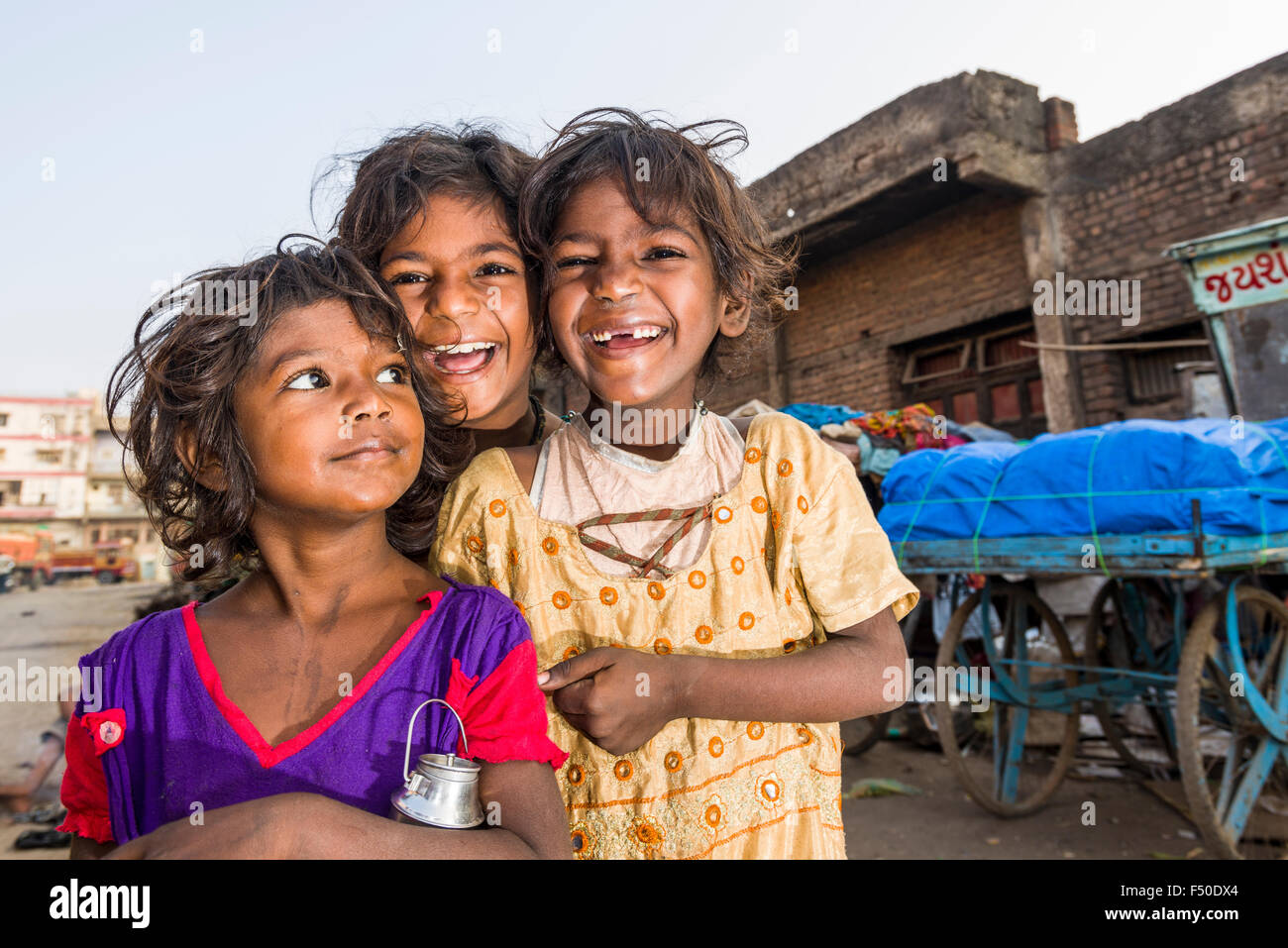 Portraits of three smiling street kids, children, who are living just beside busy roads on the pavement Stock Photo