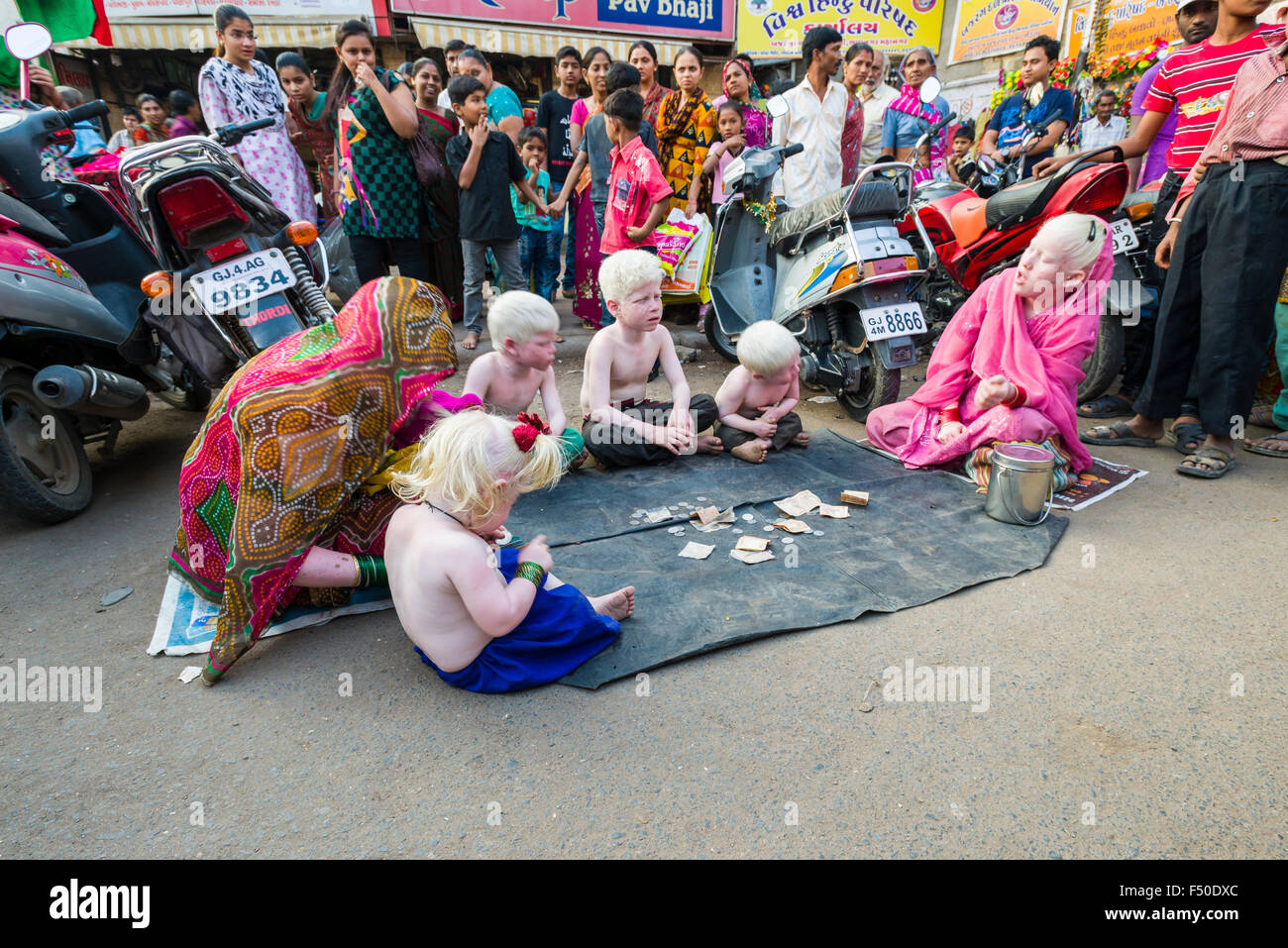 A family of Albinos, all have extremely pale skin and near-white hair, is begging for money on the street Stock Photo