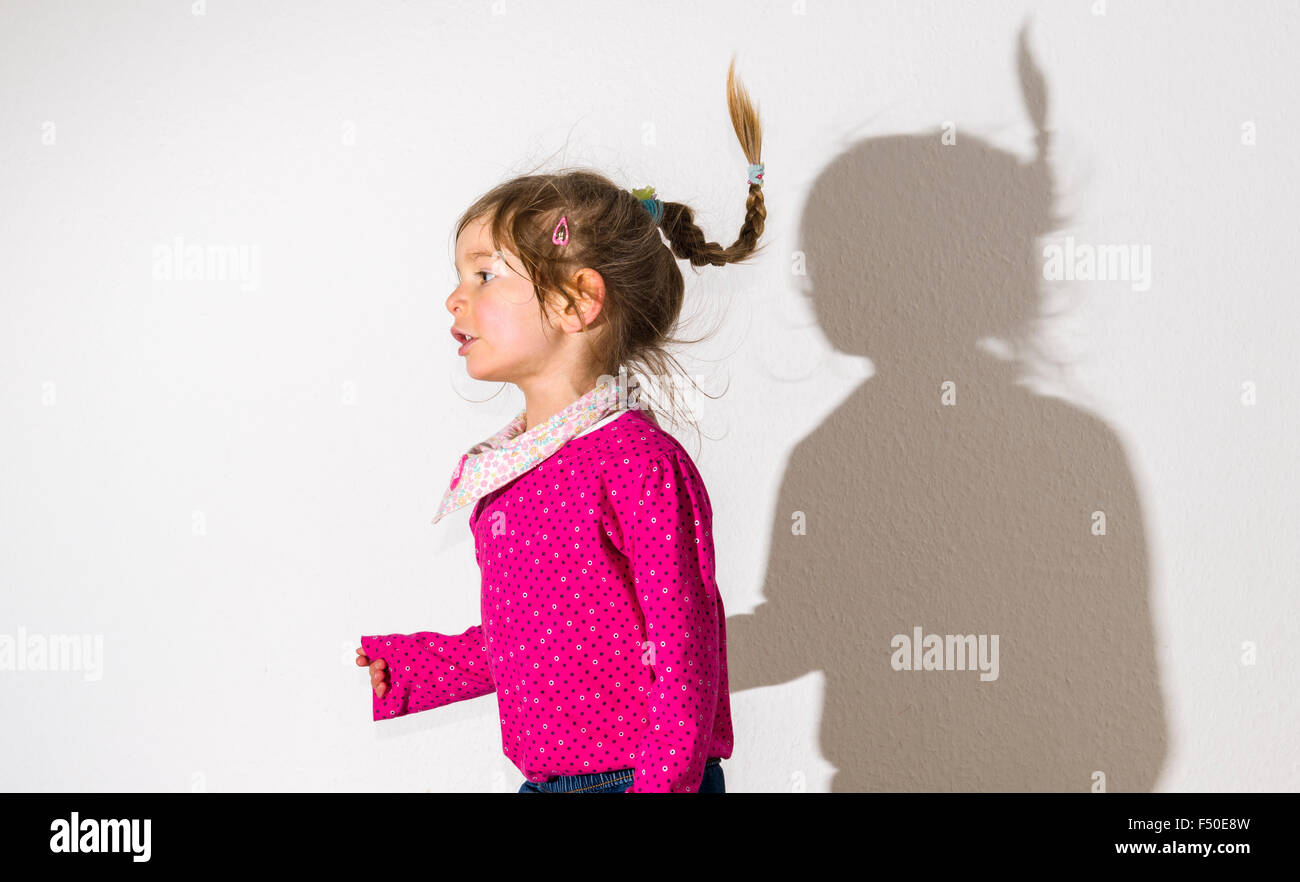 A blond three year old girl, wearing a pink shirt, is dancing in front of a  white wall, leaving her shadow behind her Stock Photo - Alamy