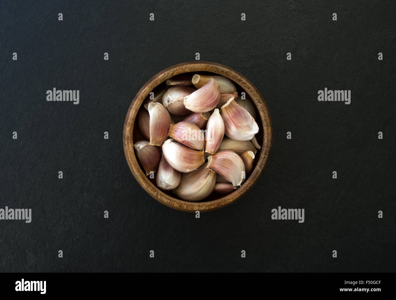 fresh garlic in a wooden bowl on black background Stock Photo