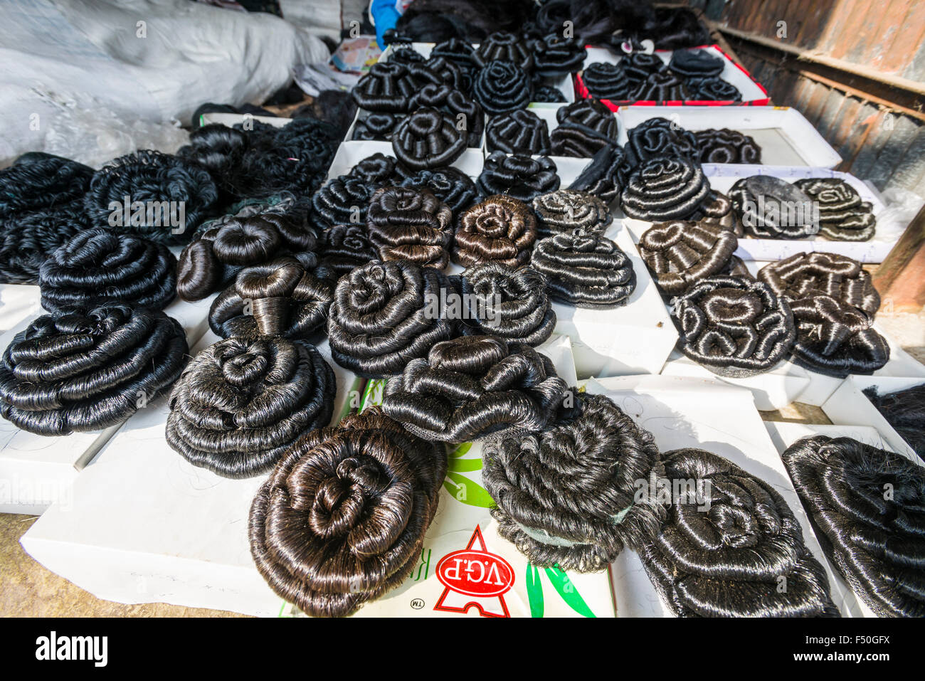 Artificial hair, braided to buns, is for sale at the weekly market Stock Photo