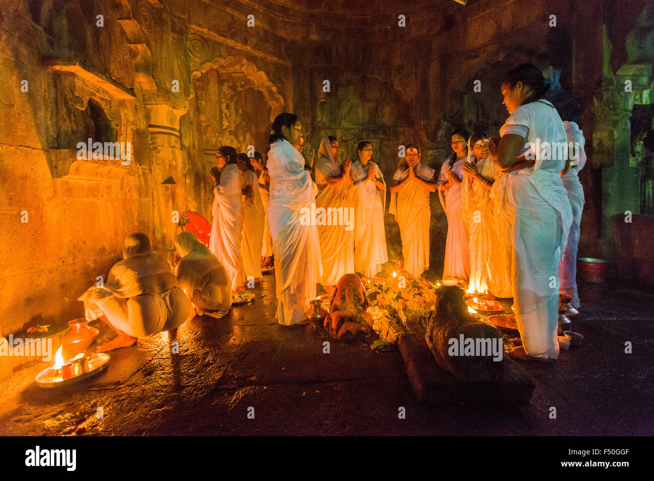A group of women is performing a ritual by using candles in the one of the temples at night Stock Photo