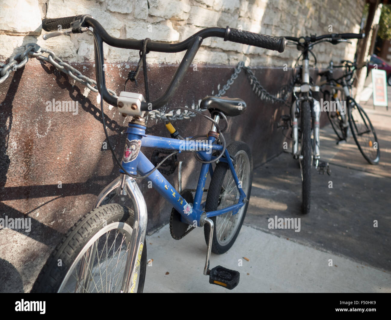 Bicycles locked up to a metal chain in an urban environment Stock Photo