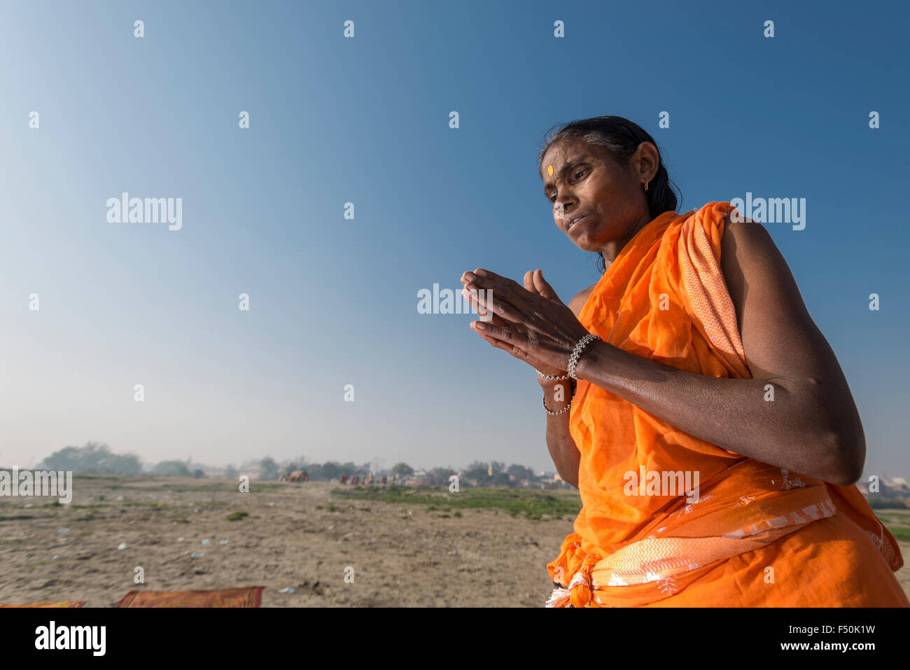 One female pilgrim, woman, is praying after taking bath in the holy river Yamuna Stock Photo