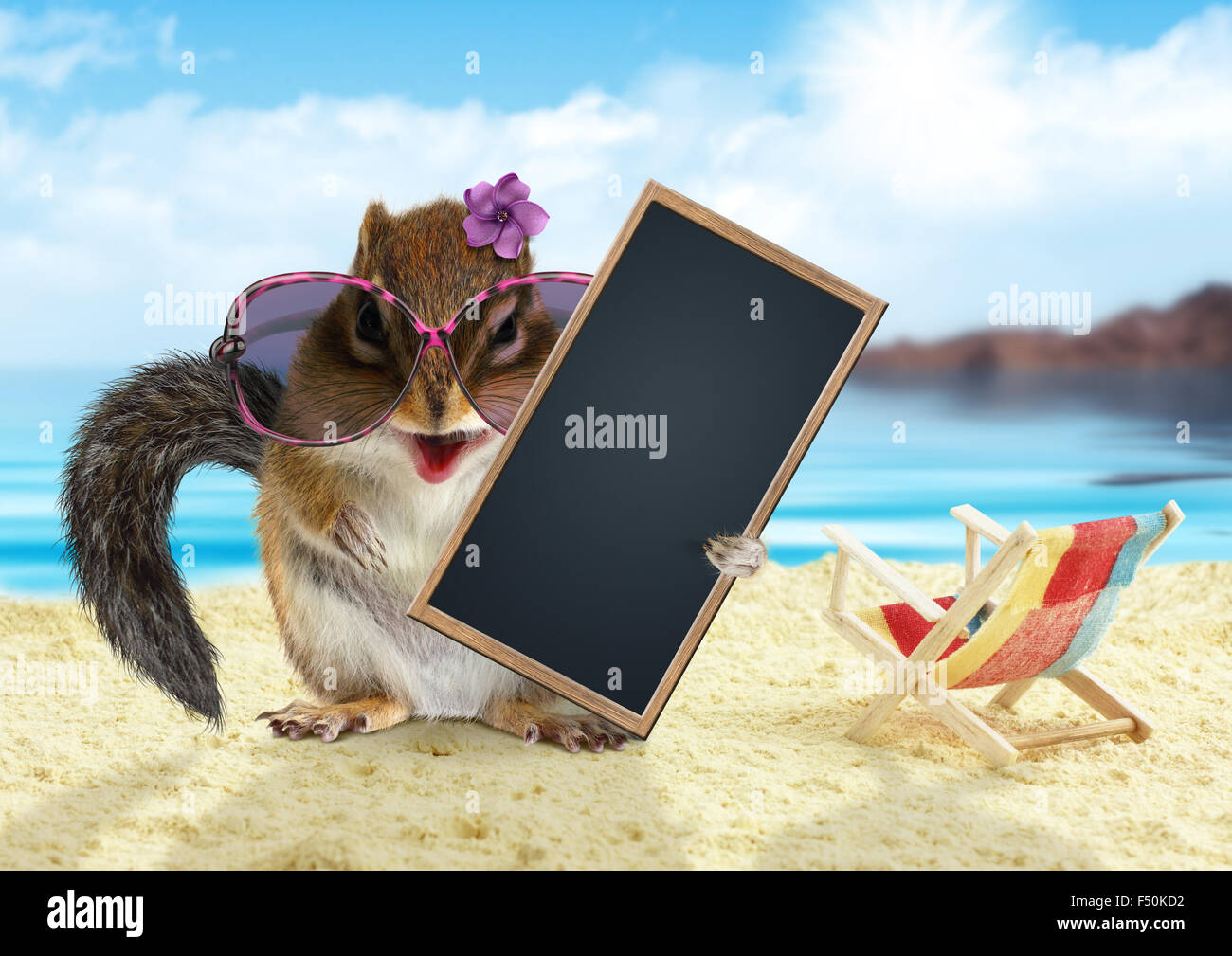 Funny chipmunk on summer vacation holidays hold empty blank banner, sitting on the beach Stock Photo
