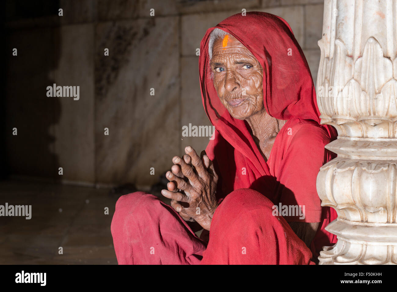 An old woman, dressed in a red sari, is praying inside Karni Mata Temple, a  famous Hindu temple dedicated to Karni Mata. It is a Stock Photo - Alamy