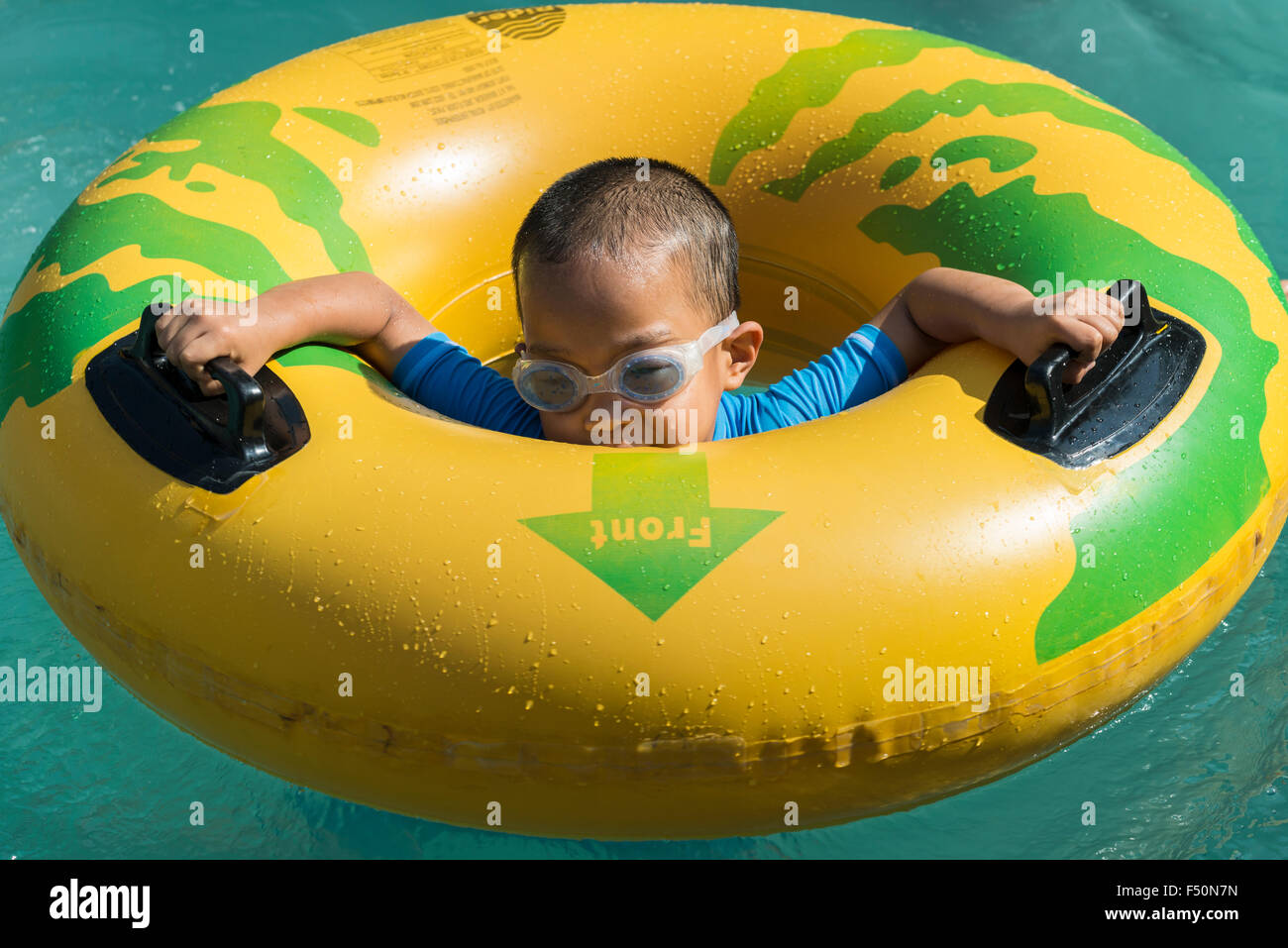 A little boy is playing in a yellow swim ring at Wonder La, the big amusement park outside of Bangalore. The park features a wid Stock Photo