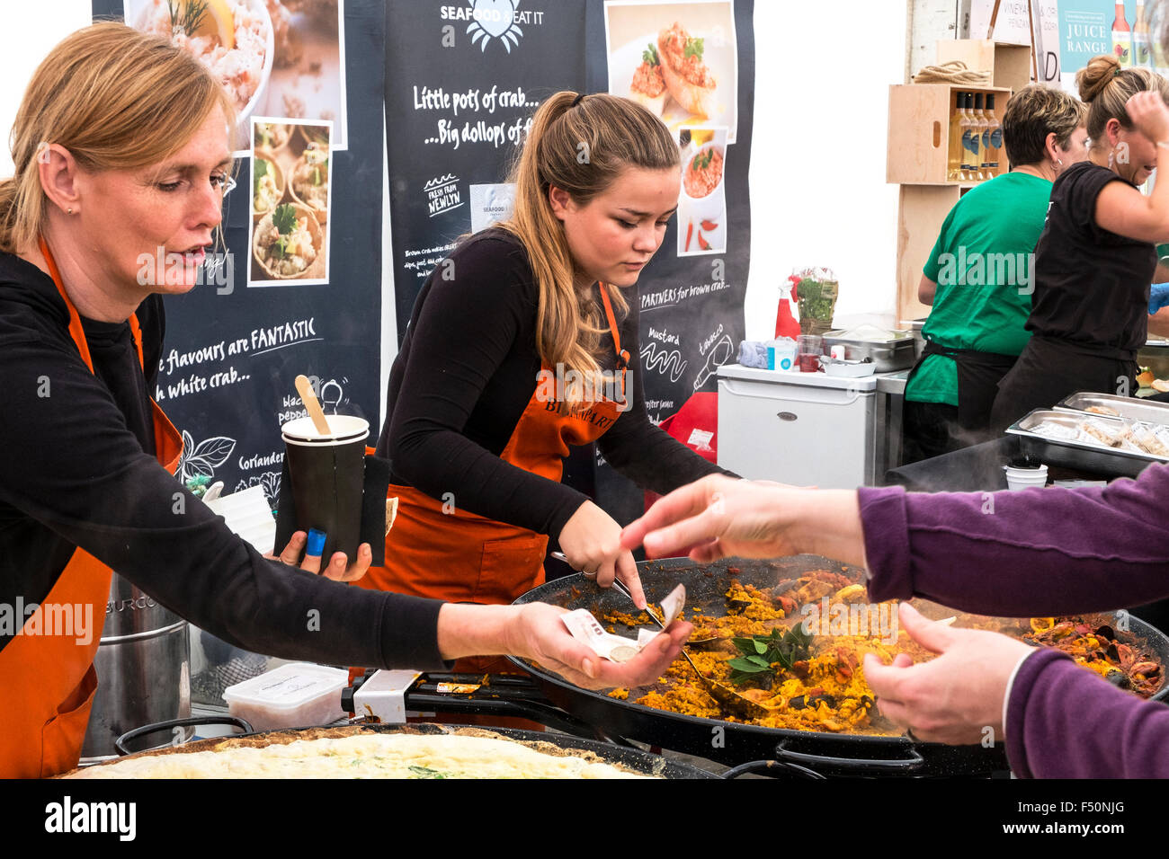 two young women serving food from a market stall in truro, cornwall, uk Stock Photo