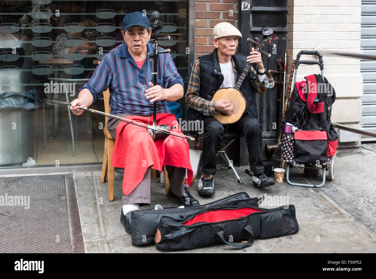Two senior Asian busker musicians playing Chinese music on erhu and ruan in Chinatown in New York City Stock Photo