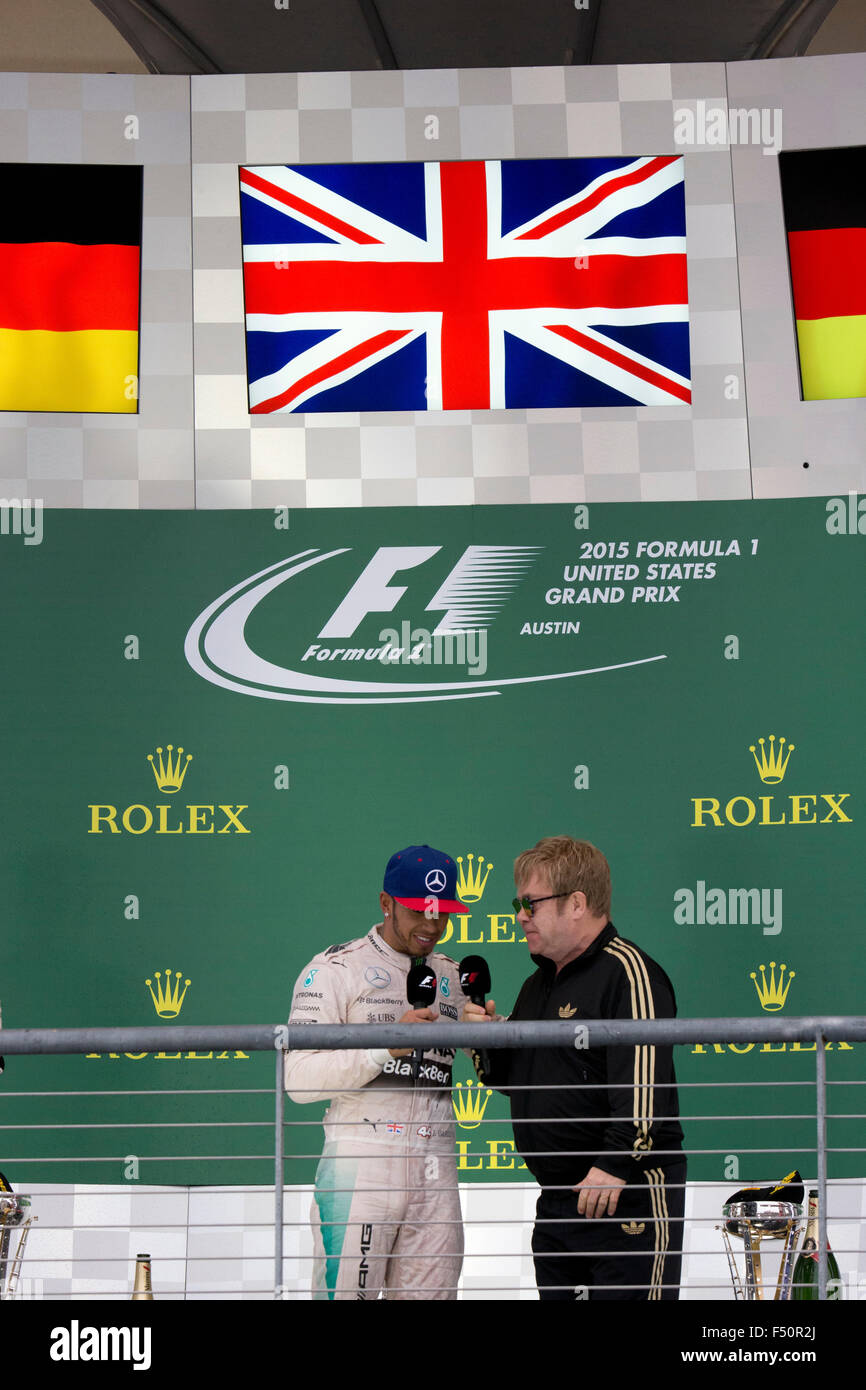 Austin, TX USA October 25, 2015: Formula 1 driver Lewis Hamilton talks to Sir Elton John as he celebrates his victory over teammate Nico Rosberg in the United States Grand Prix that clinched his world championship title. Stock Photo