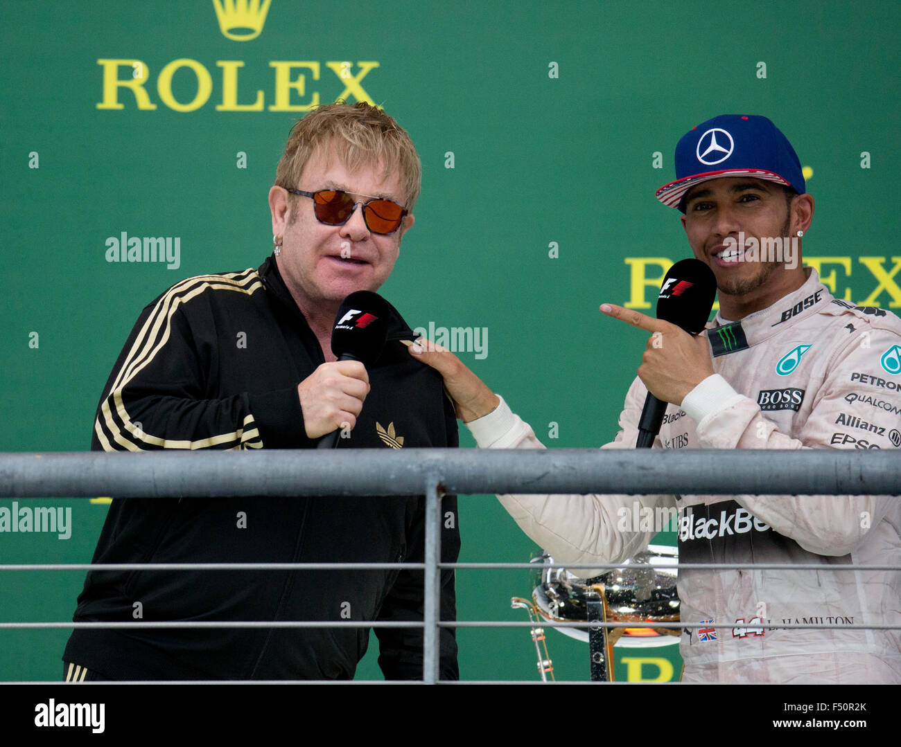 Austin, TX USA October 25, 2015: Formula 1 driver Lewis Hamilton, left talks with Sir Elton John as he celebrates his victory over teammate Nico Rosberg in the United States Grand Prix that clinched his world championship title. Stock Photo