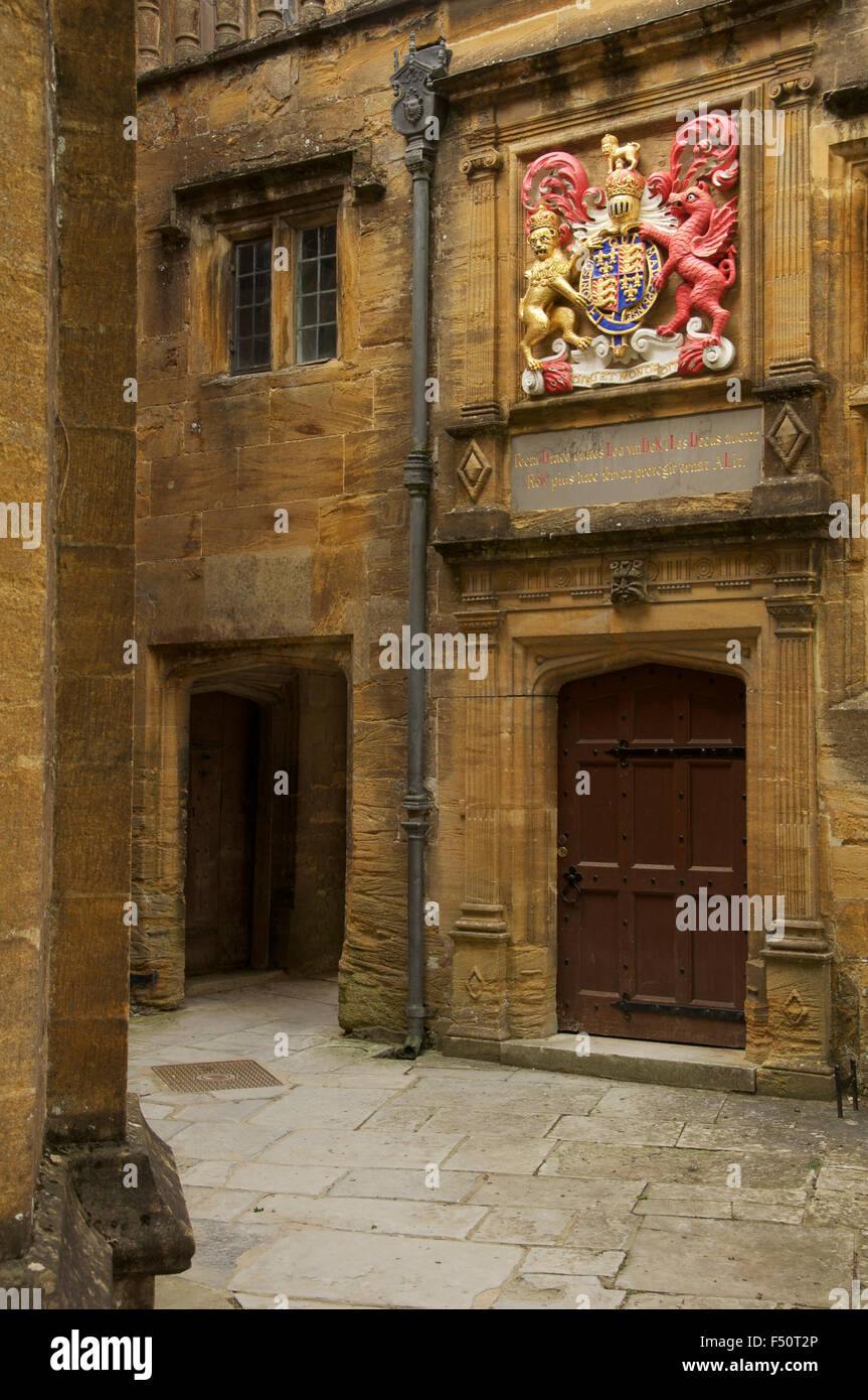 A small secluded courtyard in Sherborne School. Above a doorway is the Royal Coat of Arms of King Edward 6th. Dorset, England. Stock Photo