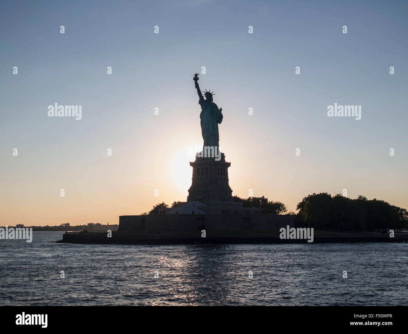 siloette against sun; Statue of Liberty; New York Stock Photo