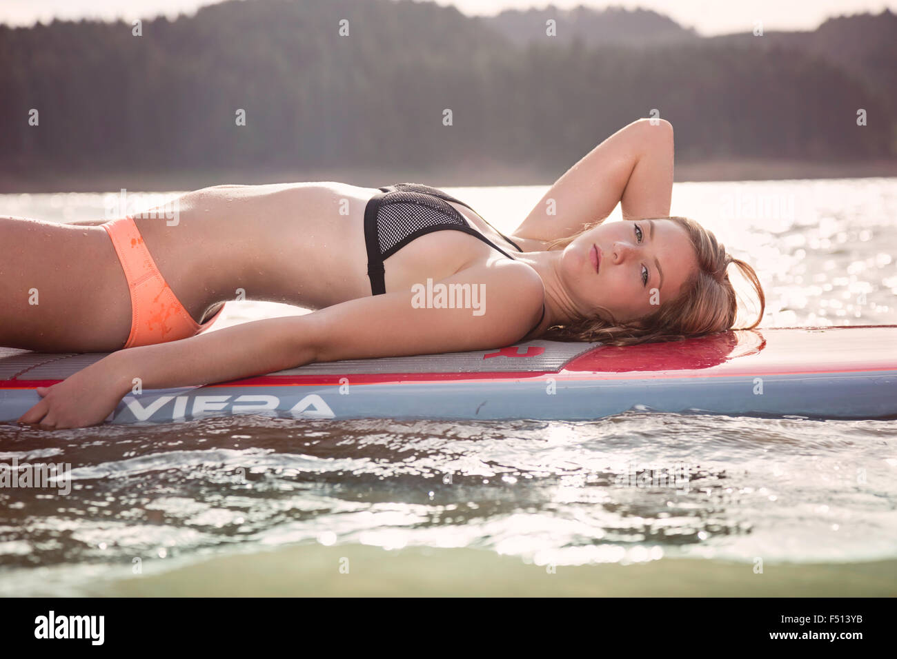 Beautiful athletic woman floating on a paddle board on a lake in the sunshine Stock Photo