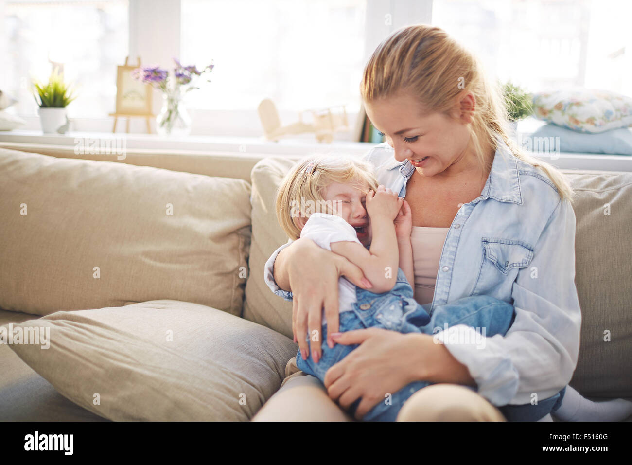 Young woman reassuring her small crying daughter Stock Photo