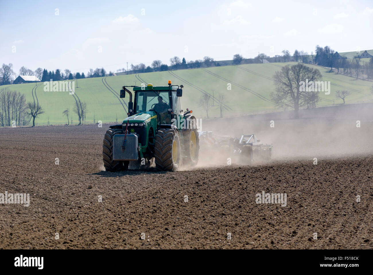 A tractor is pulling a harrow on a field Stock Photo - Alamy