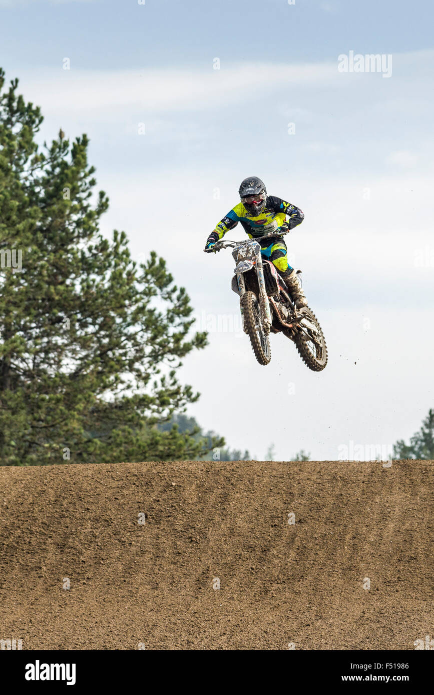 A motorcyclist on a motocross bike is jumping through the air during