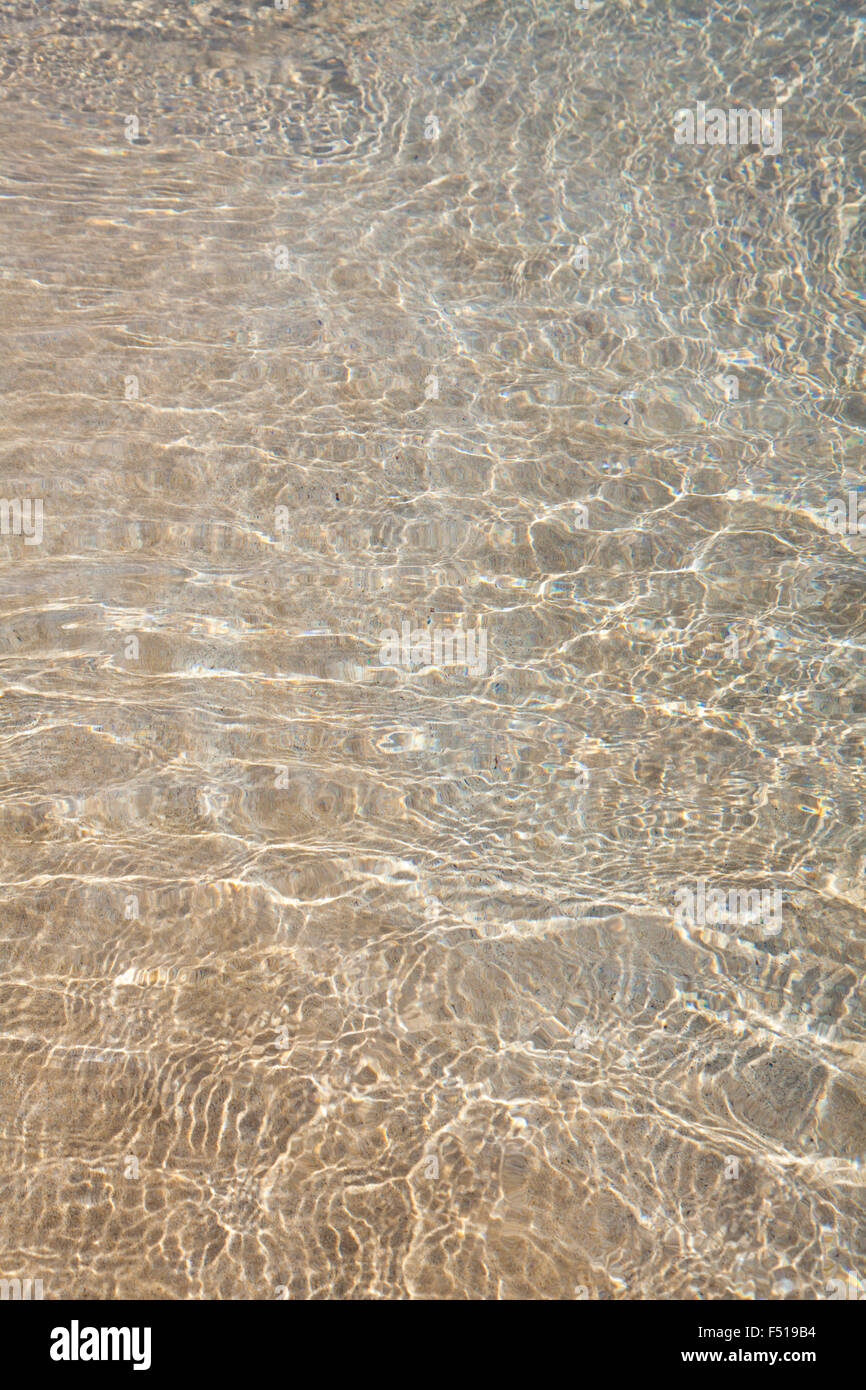 shallow rippled water over light sand, rainbow refractions, natural background Stock Photo