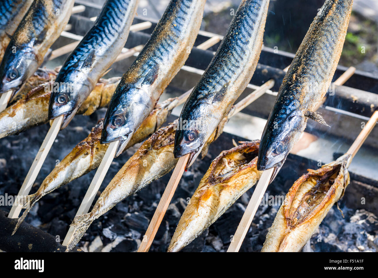 Stockfisch, a fish dish prepared on a wooden stick, is grilled on a BBQ Stock Photo