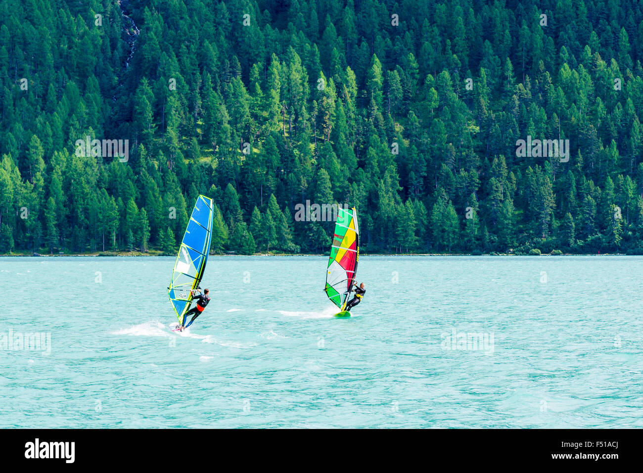 Two Surfers are crossing the Lej da Silvaplana, a high altitude lake near St. Moritz Stock Photo