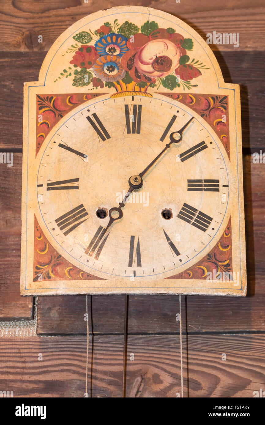 vintage kitchen clock with Roman numbers hanged on wooden background