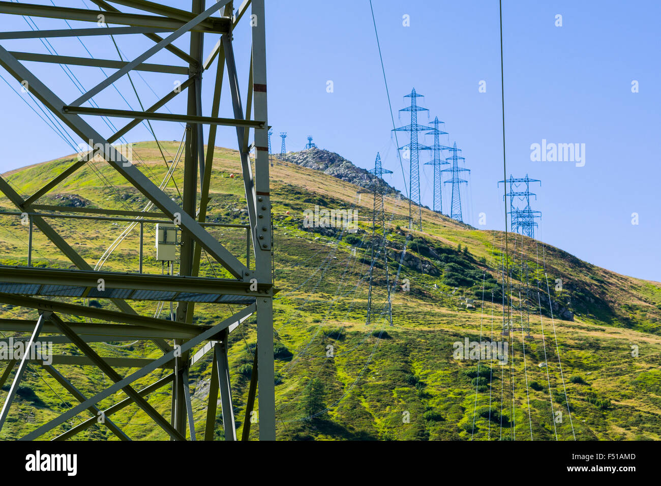 An electricity line is crossing green mountains slopes in high altitude Stock Photo