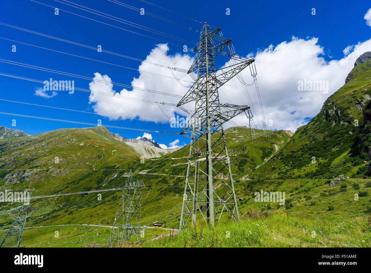 An electricity line is crossing green mountains slopes in high altitude Stock Photo