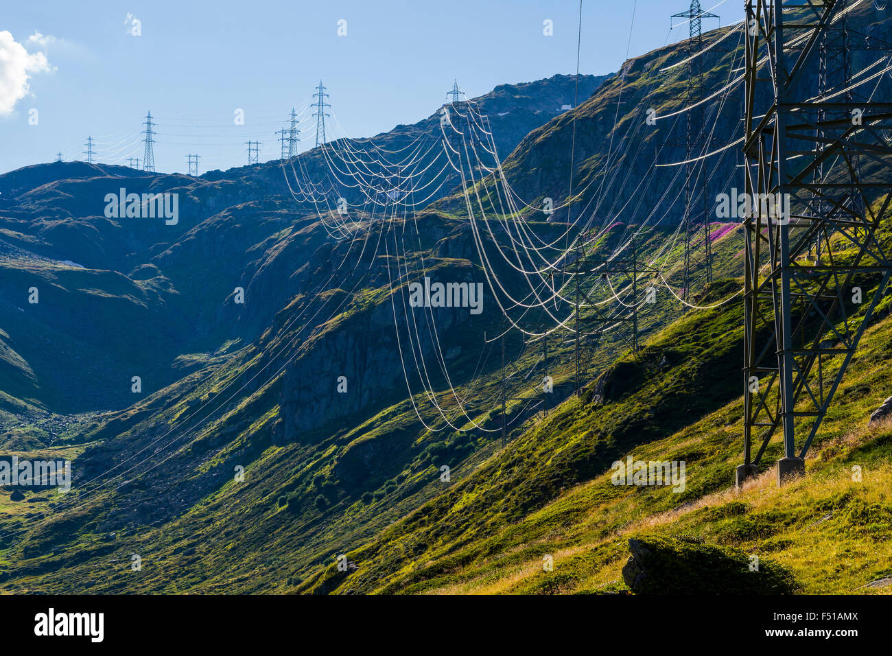 An electricity line is crossing green mountains slopes in high altitude near Nufenenpass Stock Photo