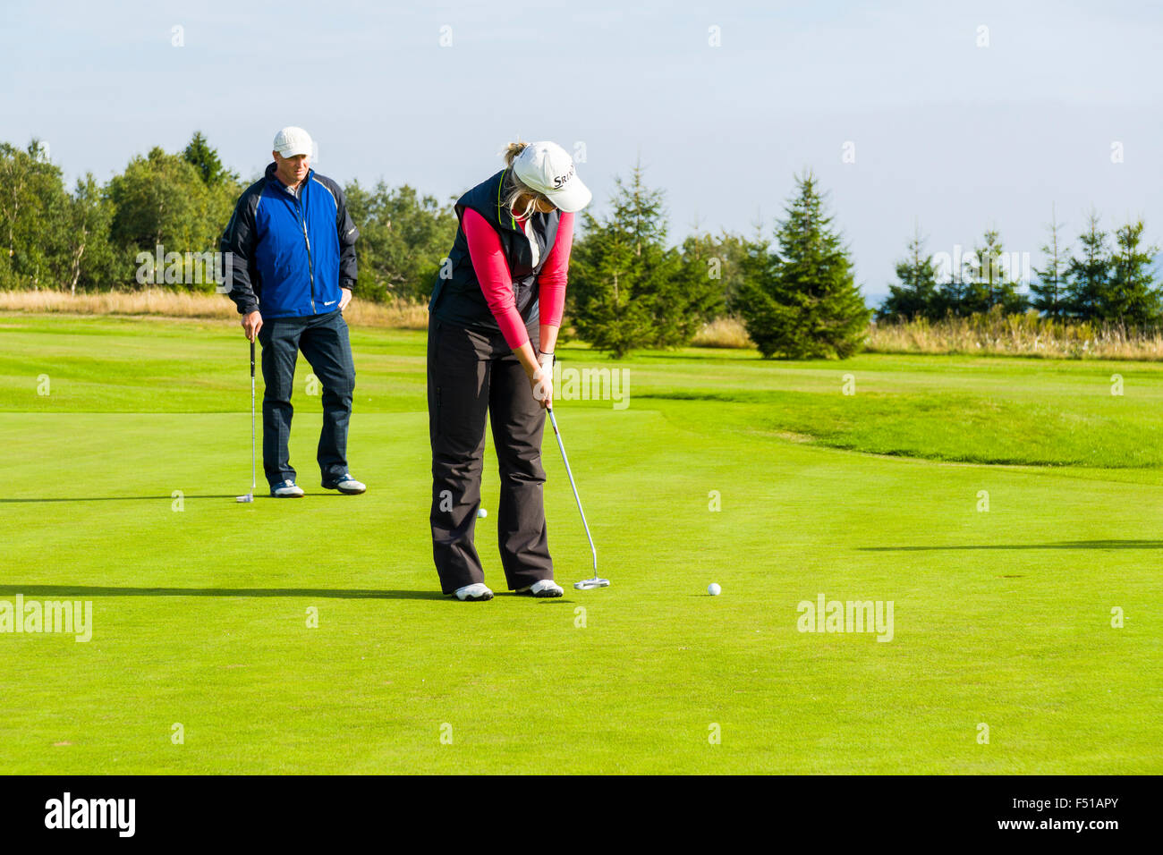 A man and a woman are playing golf on a green meadow Stock Photo
