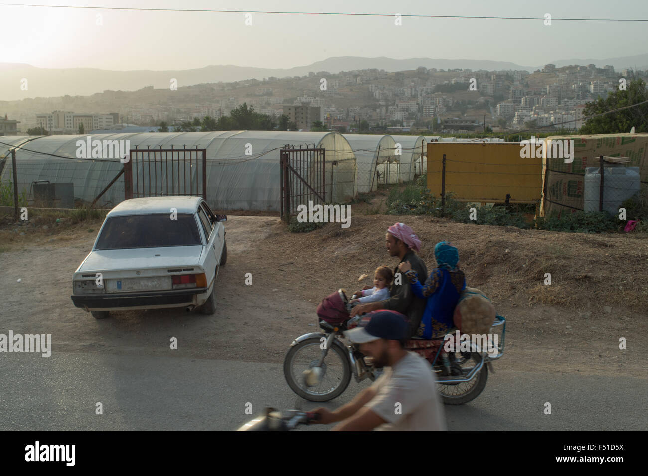 Syrian refugee on motobike comong back from work to the camp in the Bekka Valley. Zahle, Lebanon. July 2015 Stock Photo