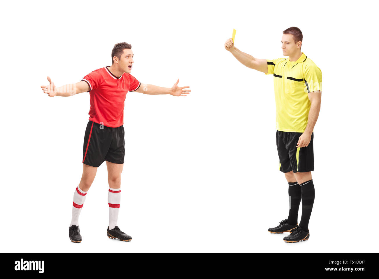 Full length portrait of a football referee showing a yellow card to a displeased player isolated on white background Stock Photo