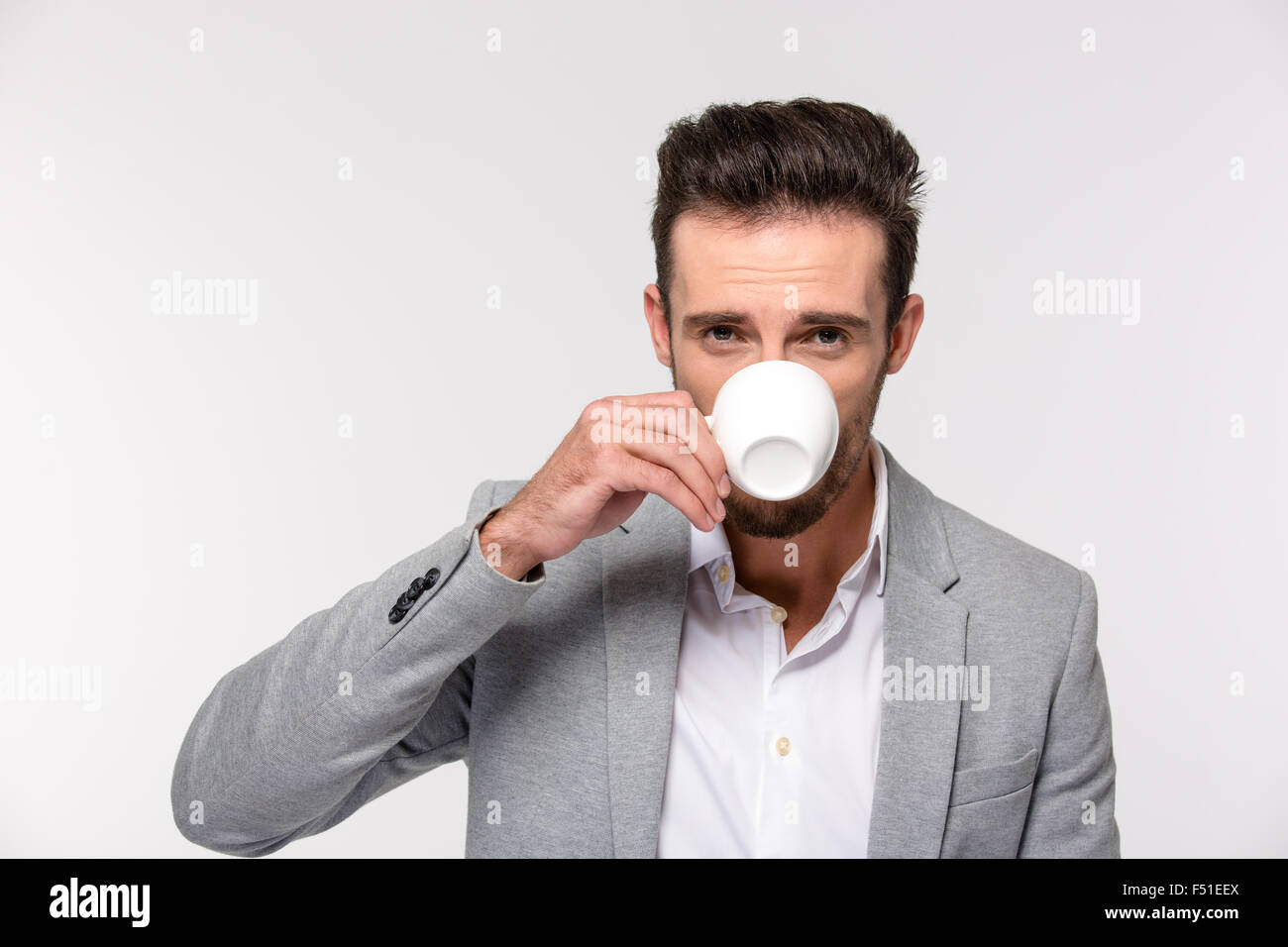 Portrait of a handsome businessman drinking coffee and looking at ...